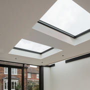 Two skylights in a modern ceiling with a view of a house exterior.