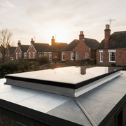 Flat roof of a building with a rooflight and a sunset over residential houses in the background